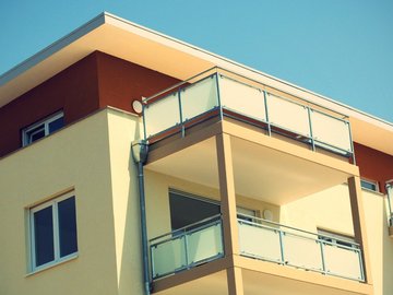 Das Bild zeigt die Außenfassade eines Apartmentkomplexes, der in Gelb- und Ockertönen gehalten ist.  