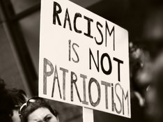 Das Foto zeigt ein Demoplakat, auf dem steht: "Racism is not Patriotism"
