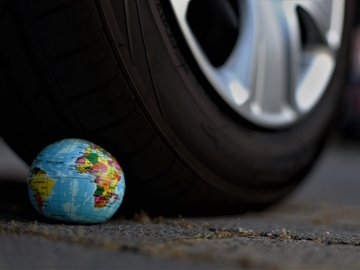 Das Foto zur Erklärung "300 Euro für Kinder, 6.000 für Autos" zeigt einen kleinen Spielzeug Globus, der von einem Auto überfahren wird