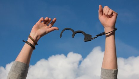 Das Foto zur Pressemitteilung der Linken NRW zum Weltdrogentag zeigt eine Person, die an einem Handgelenk eine Handschelle trägt.