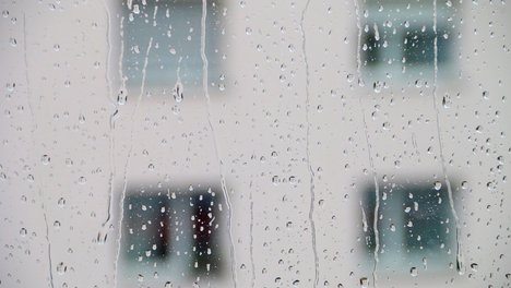 Das Foto zeigt eine Fensterscheibe, auf der Regentropfen zu sehen sind. 