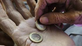 Das Bild zeigt die Hände einer alten Person, die zwei Euro halten. 