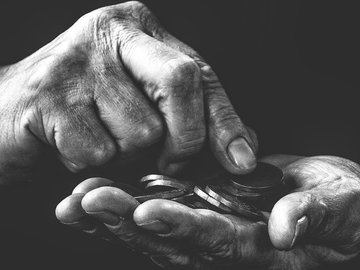 Das Bild in schwarz-weiß zeigt zwei Hände mit Kleingeld.