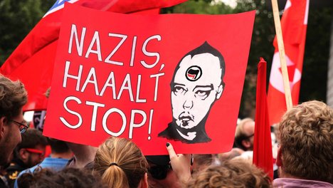 Das Bild ist eine Fotografie von einem Demo-Plakat, auf dem steht: Nazis halt Stop. Daneben ist ein Kopf mit Logo der Antifa zu sehen.