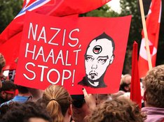 LINKE NRW Rechtsextreme Das Bild ist eine Fotografie von einem Demo-Plakat, auf dem steht: Nazis halt Stop. Daneben ist ein Kopf mit Logo der Antifa zu sehen.