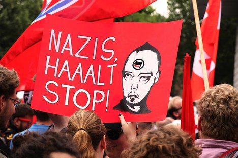 Das Bild ist eine Fotografie von einem Demo-Plakat, auf dem steht: Nazis halt Stop. Daneben ist ein Kopf mit Logo der Antifa zu sehen.