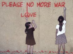 Das Foto zum Aufruf der Linken NRW zur Teilnahme an virtuellen Ostermärschen 2020 zeigt zwei Mädchen, die Make Love not War auf eine Hauswand schreiben.