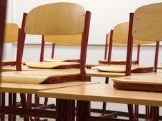 Das Foto zeigt ein leeres Klassenzimmer, in dem die Stühle auf die Tische gestellt sind. 