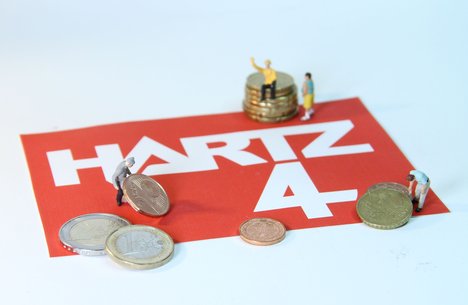 Das Foto zur Pressemitteilung der Linken NRW zu Laumanns Hartz IV-Sanktionen zeigt den Schriftzug Hartz IV. Darauf mühen sich kleine Figuren mit Kleingeld ab.